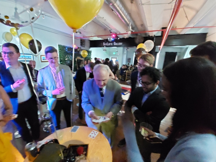Guests gathered around close-up magic performance during a private party at SkyLofts Gallery event venue.