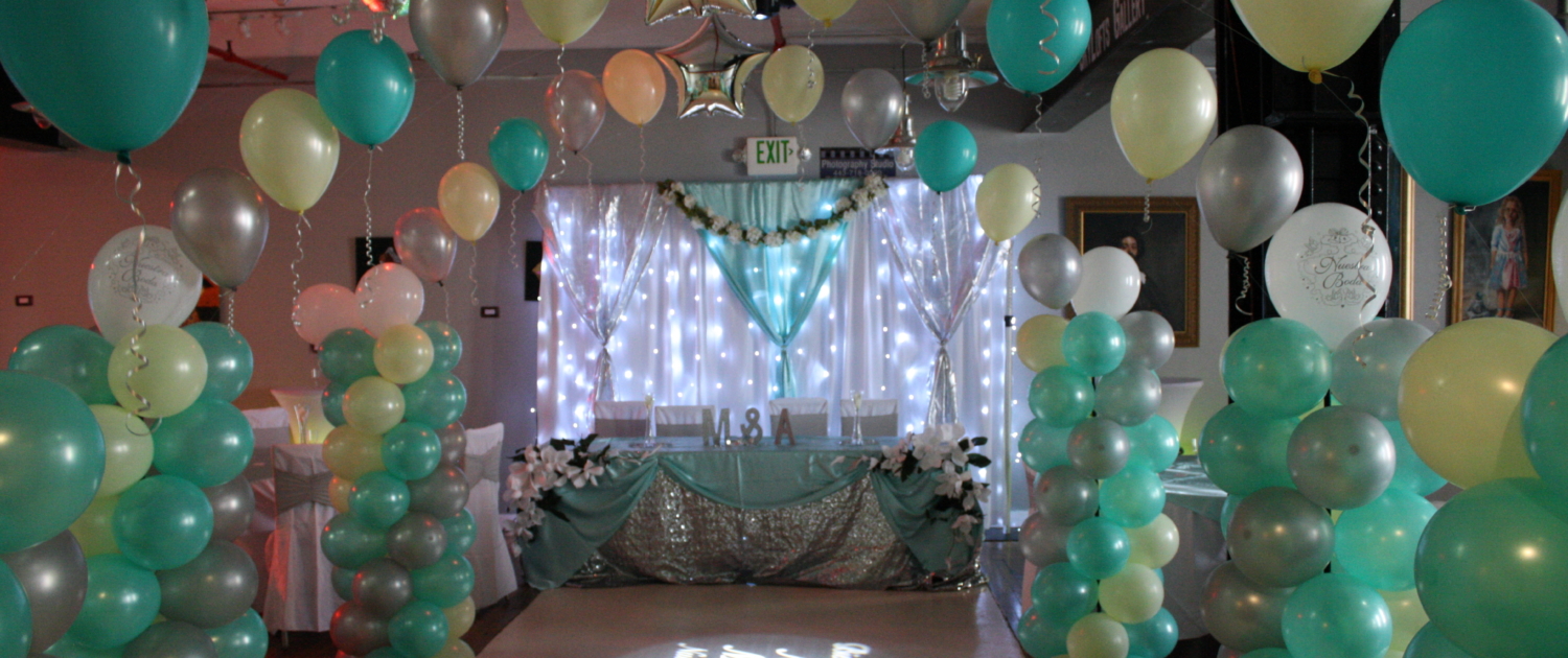 Balloon arch walkway leading to a sparkling sweetheart table under illuminated backdrop at SkyLofts Gallery party venue.
