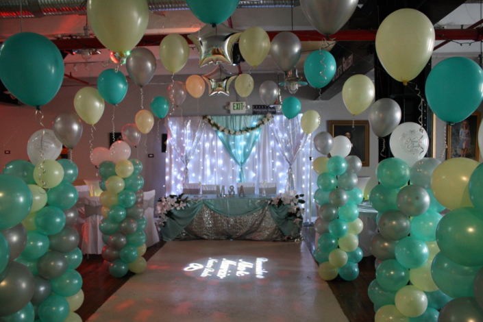 Balloon arch walkway leading to a sparkling sweetheart table under illuminated backdrop at SkyLofts Gallery party venue.